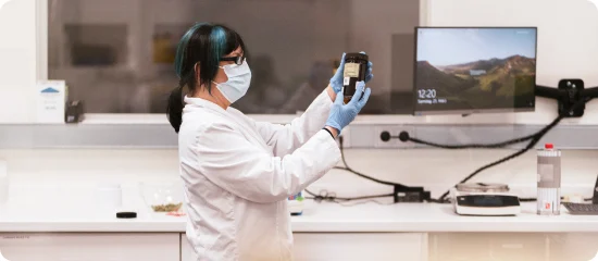Eine Mitarbeiterin der Cannabis Apotheke inspiziert im Labor ein Braunglas mit medizinischem Cannabis.