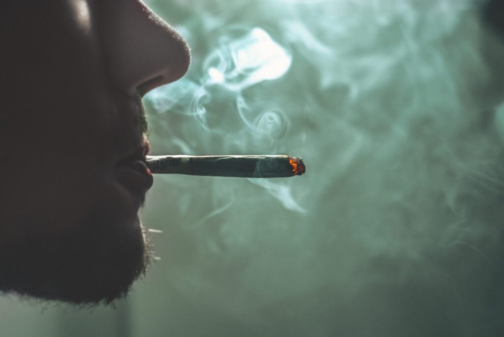 Ein Mann im Profil raucht einen Joint.