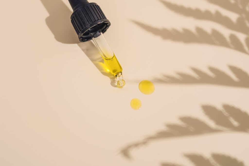 Eine Pipette mit öliger Lösung Medizinalcannabis gefüllt und der Schatten eines Cannabisblattes