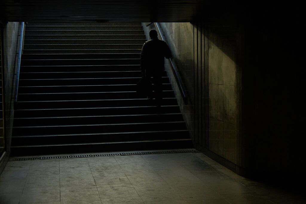 Ein Mann läuft auf der Treppe aus einem dunklen U-Bahnschacht nach oben.